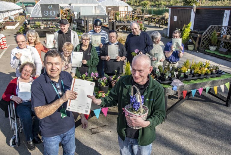 Member of New Leaf standing outside with certificates.