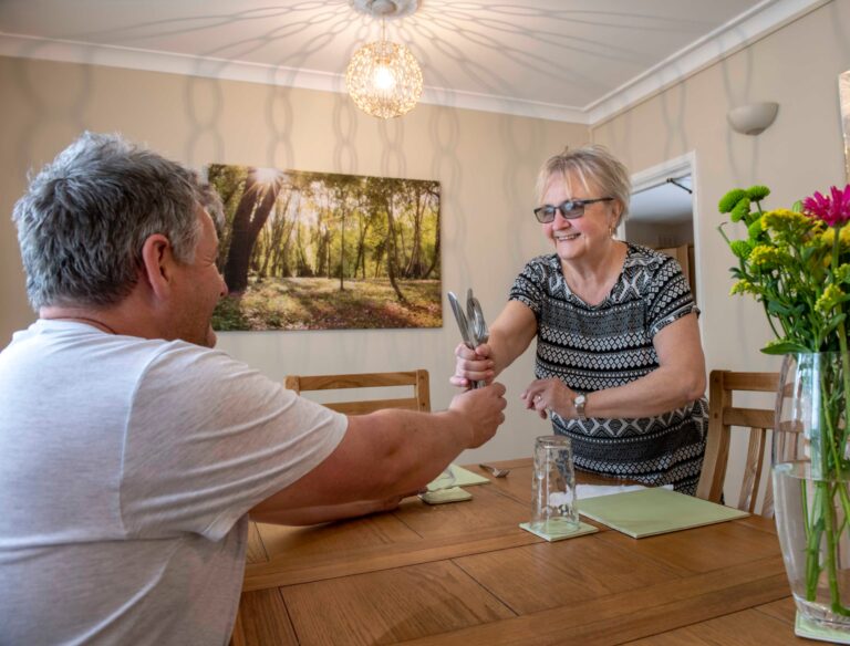 Woman passing cutlery to a man sat at a table