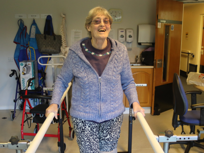 Smiling woman learning to walk on prostetic leg.