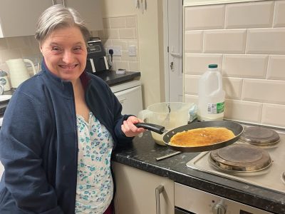 A member of supported living making pancakes