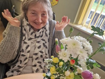 Elderly woman smiling with flowers