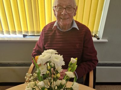Elderly man smiling with flowers