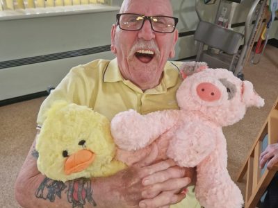 Elderly man smiling with stuffed animals